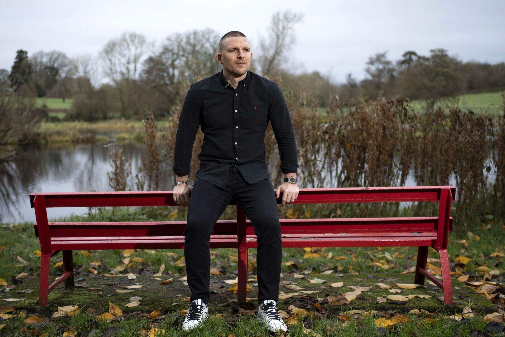 Andrew Conway sitting on a bench beside a river.